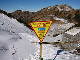 赤と黄色と水色を用いた逆三角形の「これよりさき有毒ガス滞留地帯」の警告看板