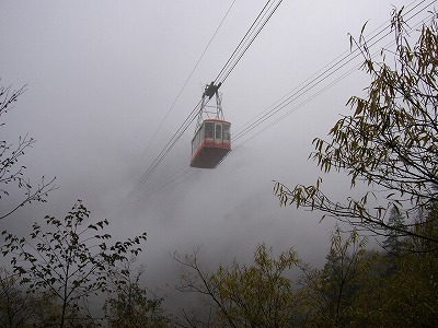 濃く重そうな霧の中ロープウェイの車体が消えて行く