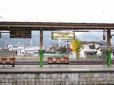 石造りのホームと屋根、駅名標。向こうは住宅街