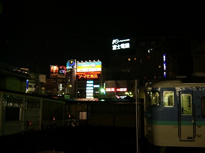 ホームから一部視界をさえぎられて駅前のネオンを見る