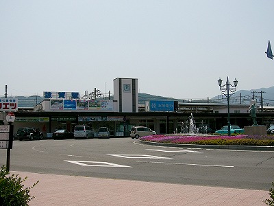 白い駅舎は平屋で、2階から3階にかけての部分に直方体の時計塔がある。それより右側には駅舎屋根の向こうにホームの上屋が見える。