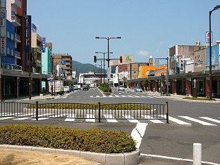 道路のほぼ真中を見て。道の両脇に建物。真中はグリーンベルト。空は完全に晴れている。