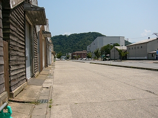 焦げ茶の長い横板でできた倉庫の端から道路の行く先を望んで。