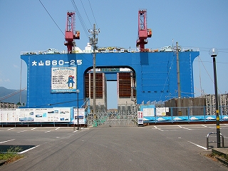 真っ青な鋼鉄の凱旋門のようなもの。工事中らしいようすで赤いクレーンが2機天辺に並んでいる。