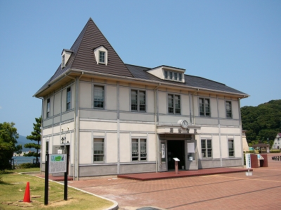 城に近いクリーム色の外壁の洋館。屋根の左側だけとがっている。入り口正面に丸い時計が付けられてある。