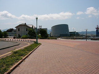 左端にアスファルトの道路が少し、右に港の海が少し写っている。真中はレンガのカーブした広場。