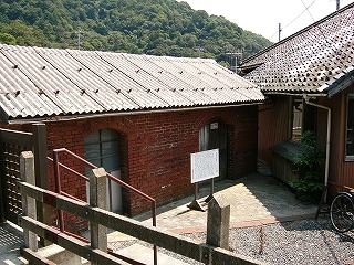 左に平屋のランプ小屋。今立っている道から少し降りた所にある。