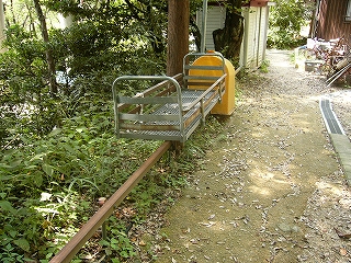 さびた一本の太いレールが地面から数十センチ高い所に作られてある。その上に金属製の網のかごを跨げてある。