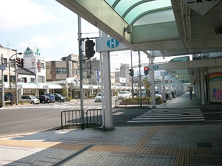 白色を基調とした真新しいアーケードの歩道。目の前に細い道が横切り、商店街の大通りに繋がっていて、その細い道を渡る横断歩道の信号機が見える。