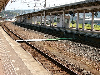 左奥の方に曲がり込んでいる6,7番ホーム。ホームの上に何か探すとすればガラス窓の入った小さな小屋と長椅子1脚があるぐらいで人はいない。保線員のための線路を渡る渡しが見えている。