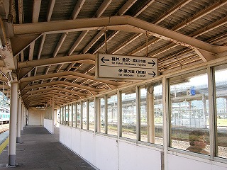 薄暗いクリーム色の上屋の下の、ホーム真ん中にサッシ窓入りの風除け。