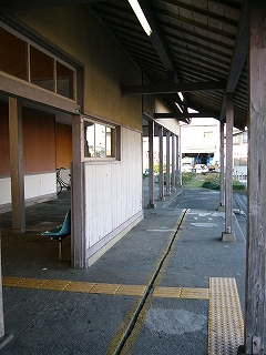 出入り口前の回廊。外へ向かって下がった屋根の下では、蛍光灯が何本か灯っている。