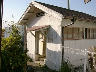 白い小さな建物。窓枠は桃色。