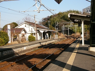 遠くにホームが切れたところで線路は左カーブ。カーブ脇に緑の木々が生い茂る。