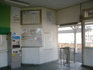 壁が斜めに切り取られた出札口跡と錆びた鉄パイプの柵のある旧改札口。