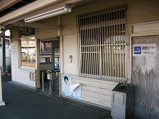 白い壁と旧改札口。窓ガラスにはステンレスの縦の桟が入れられている。