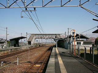 ホームと線路内。遠くに跨線橋。左手に待合所、右手に駅舎。