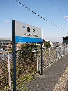 ホームに立つ駅名標。背後には新しい感じの住宅街。