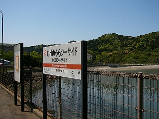 駅名標と海辺と、山の緑。