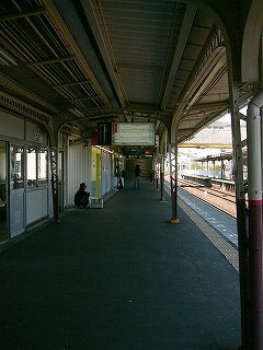 アスファルトの薄暗いホーム。右手が乗り場で光が差し込んでいる。