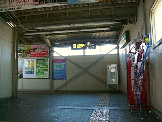 跨線橋を上り詰めたところ。掲示物などがある。窓から光が差し込んでいる。