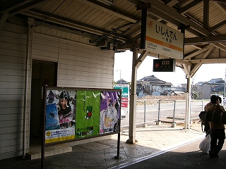 トイレ入口を左斜めに見て。入口の前には3枚ポスターの貼られたついたてがしつらえてある。上の方に駅名標。