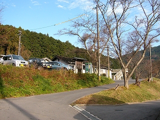 枯れた木々を挟んだヘアピンカーブの向こうに見える駅舎。