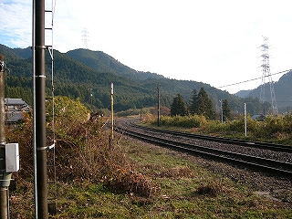山に囲まれた広い谷の高い位置を見事にカーブして行く関西本線。