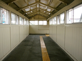 地面はアスファルト、ほかは白色の跨線橋内。