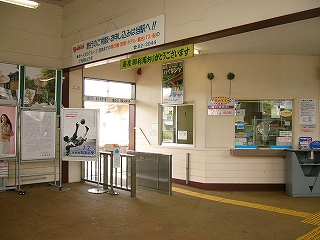 白塗りの駅舎内。有人改札のみの改札口と斜めにカットされた出札口を見て。