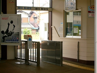 ステンレスの低い柵と低い壁で作られた簡単な改札口。右手には窓口。