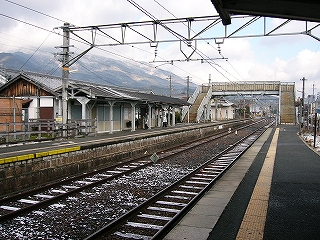 下り線ホームの上屋と跨線橋を、上り線ホームの待合所付近から見て。上屋の向こうには標高の高い生駒山地が雪を薄く被っているのが見え、山の近くにいる雰囲気がある。