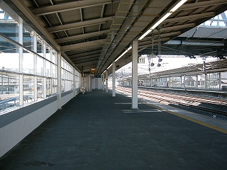 ホームの端付近から、広い左片持ちの上屋の今いるホームを眺め通して。ずいぶん先に行った所に、待合室の壁が見えている。待合室を越えてもホームは続いている。