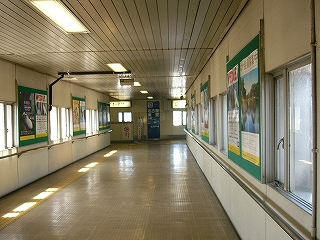 上り線ホームへの短く幅の広い跨線橋。両脇の壁にはポスターと窓が交互に現れる。