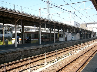 ホーム縁から2線の線路内を挟んで隣のホームを左斜めに見る。橙色のラインの入った列車が隣に見えているホームの向こう側の線に停車中