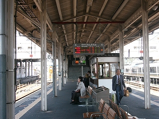 手前に椅子の並び、その奥に駅そば屋。