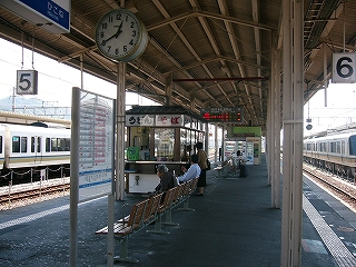 上の写真に写っているものを、正面から見直して。手前に時刻表、そして一人掛けの六連椅子、その奥に駅そば屋。さらに奥には薄緑の待合室の壁に沿って販売機が設置されている。