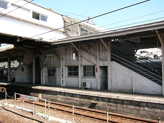 跨線橋とその階段。全体的に白っぽい色で塗られ、階段上り口脇の壁などは木造になっている。