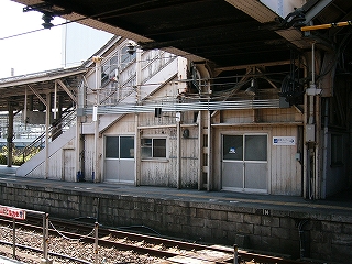 跨線橋の下付近から階段袂の木造を見る。地面に近い部分は色が黒くはげかかっている。