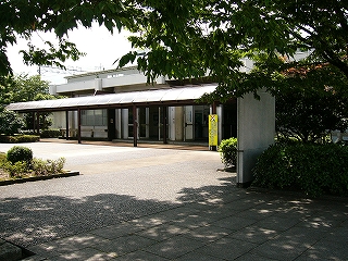 緑の葉の下から望む、駅舎入口前。人は誰もいない。