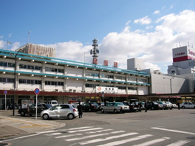 オレンジの駅名表示、水色のラインの入った3階建て駅舎。