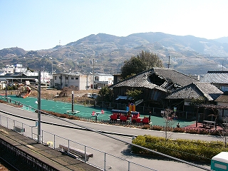 地面が緑色に整備された遊具のたくさんあるプレイランドと遠くにどっしり構える山々。