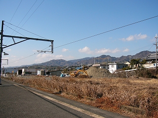 枯れ草の広場と遠くに住宅、そしてそれほど高くはない山脈。