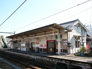 屋根瓦の白い駅舎をホーム側から見て。