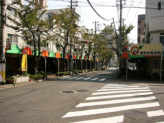 側面に緑とオレンジ色の半円の並ぶアーケードの通り。