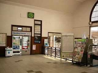 左手に壁に埋め込まれた改札内の自販機二台。その壁と直角に駅舎内を改札内と改札外に分ける低い柵。