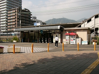 平屋の簡易な建造物。手前がカールした波板の屋根の上に「JR灘駅」の表示、屋根の下は少し暗く、自動改札が並んでいる。