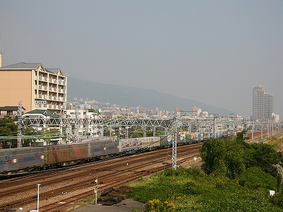 左斜めに横切る太い東海道本線。ずっと向こうの方に緩やかな斜面にできた街。