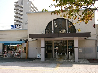 2階分の高さの立方体のような建物。上方に半円の窓、その下から手前まで屋根が出ていて、その下に駅舎の出入口。