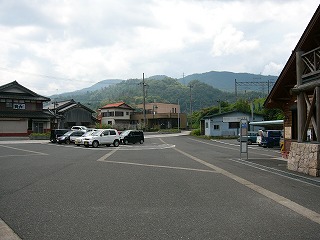 広々としたアスファルトの敷地の真ん中にぽつんたとロータリー、向こう側は家々、ずっと向こうは山々。